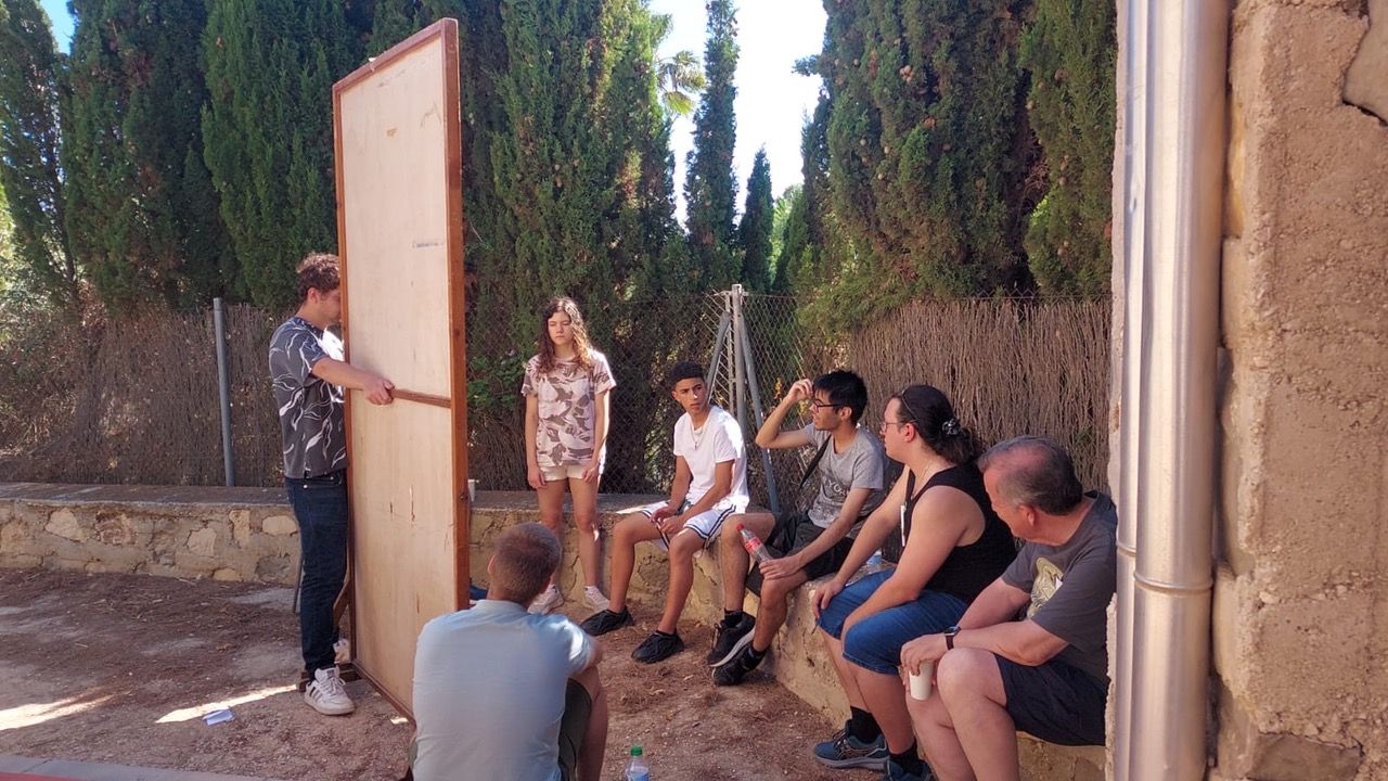 Grupo de personas observando a un chico explicar algo en una pizarra.